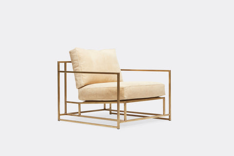 side of armchair with cream color leather upholstery on antique brass metal frame
