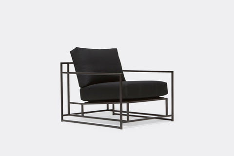 side of armchair with black canvas upholstery on black metal frame