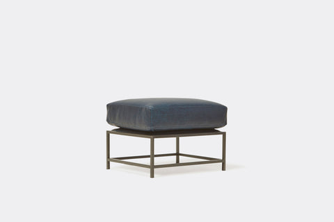 side of ottoman with navy leather upholstery on black metal frame