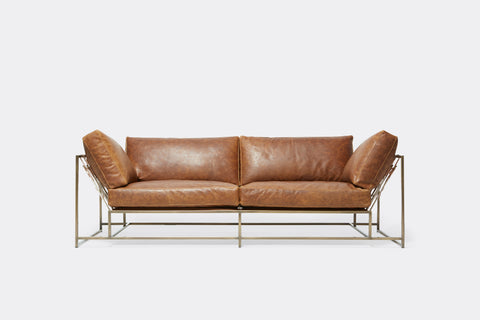 Front of two seat sofa with brown leather upholstery and antique brass metal frame