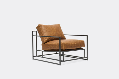 side of armchair with brown leather upholstery on black metal frame