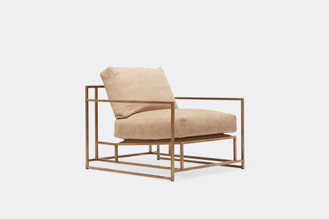 side of armchair with tan leather upholstery on antique brass metal frame