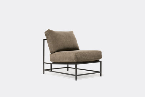 side of lounge chair with grey velvet upholstery on black metal frame
