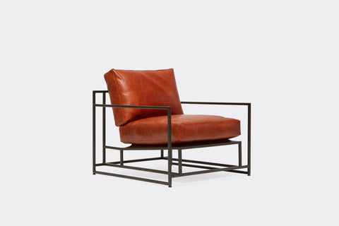 side of armchair with brown leather upholstery on black metal frame