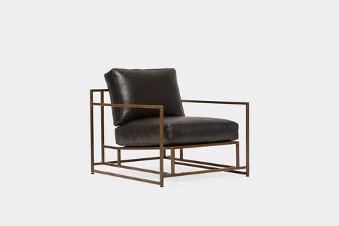 side of armchair with black leather upholstery on antique brass metal frame