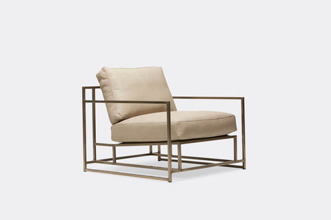 side of armchair with cream color leather upholstery on antique nickel metal frame