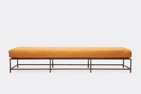 front of bench with tan leather upholstery on marbled rust metal frame.