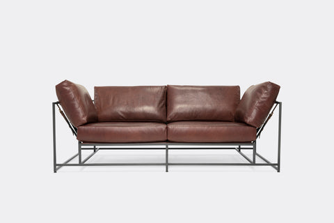 Front of two seat sofa with brown leather upholstery and black metal frame