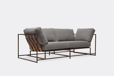 side of two seat sofa with grey wool upholstery and brown leather belts on marble rust metal frame