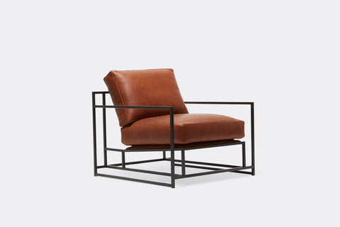 side of armchair with brown leather upholstery on black metal frame