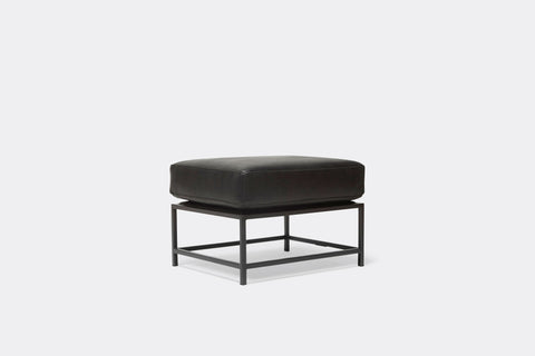 side of ottoman with black leather upholstery on black metal frame