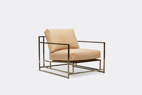 side of armchair with tan leather upholstery on polished black nickel metal frame
