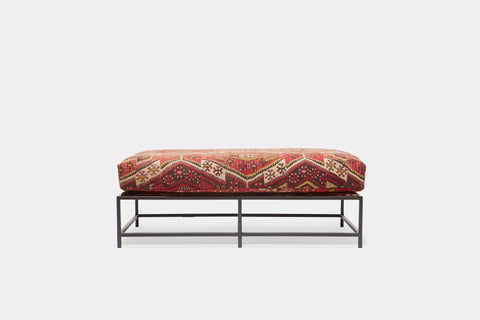 front of bench with antique rug upholstery on black metal frame