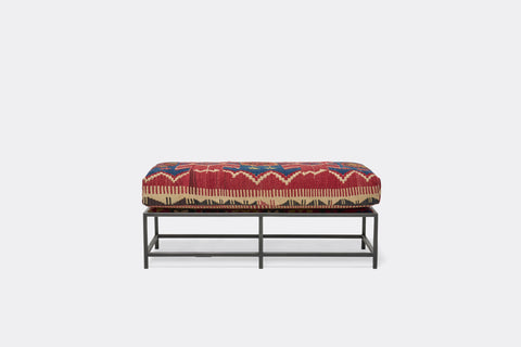 front of bench with antique rug upholstery on black metal frame