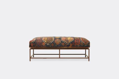 front of ottoman with antique rug upholstery on marbled rust metal frame