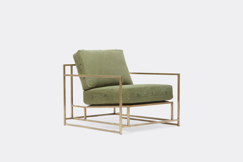 side of armchair with green canvas upholstery and black leather belts on antique brass metal frame