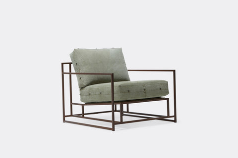 side of armchair with green canvas upholstery on marble rust metal frame