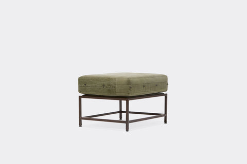 front of ottoman with green canvas upholstery on marble rust metal frame