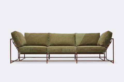 front of sofa with green canvas upholstery on marbled rust metal frame