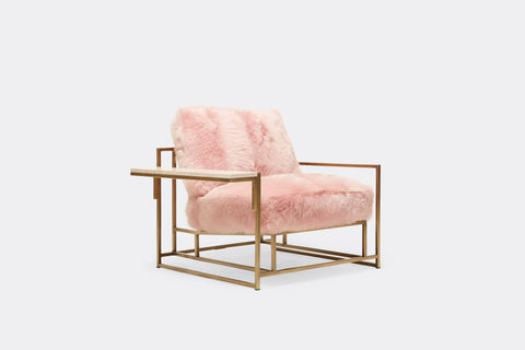 side of armchair with pink shearing upholstery on antique brass metal frame