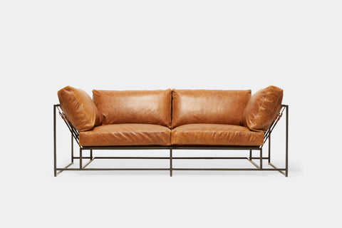 front of two seat sofa with brown leather upholstery and black metal frame