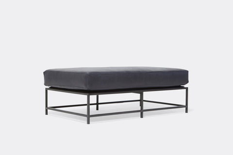 side of bench with blue leather upholstery on black metal frame