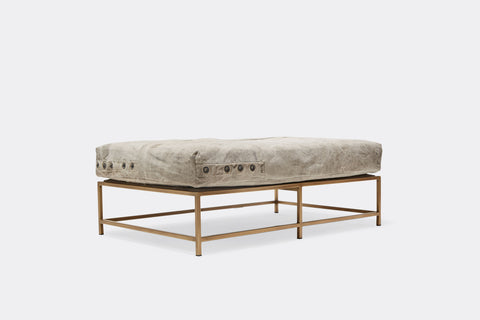 side of bench with grey canvas upholstery on antique brass metal frame