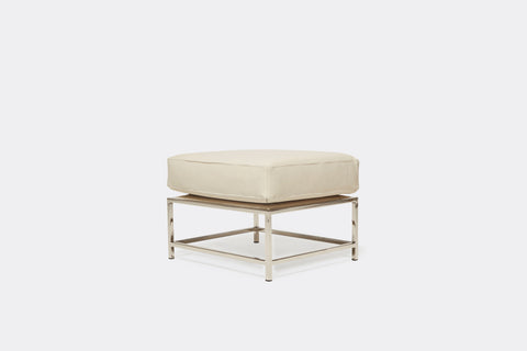 side of ottoman with cream leather upholstery on polished nickel metal frame